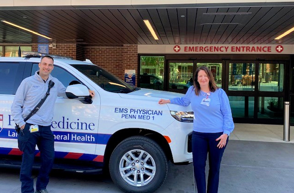Two Penn Medicine Lancaster General Health employees stand beside the Physician Response Vehicle, parked outside of the Emergency Room entrance.